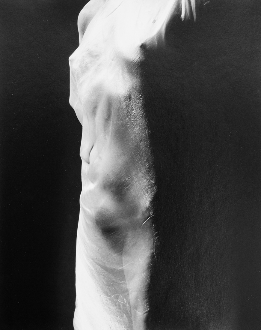Black and white image of a woman's torso, indistinct features seen through gauzy fabric.
